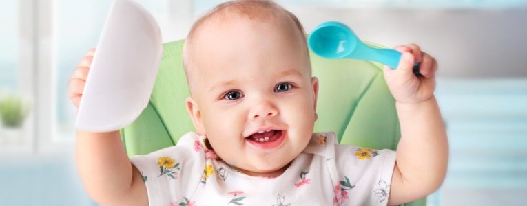 Child waiting for food with a smile holding spoon and plate