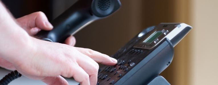 A person typing number on telephone